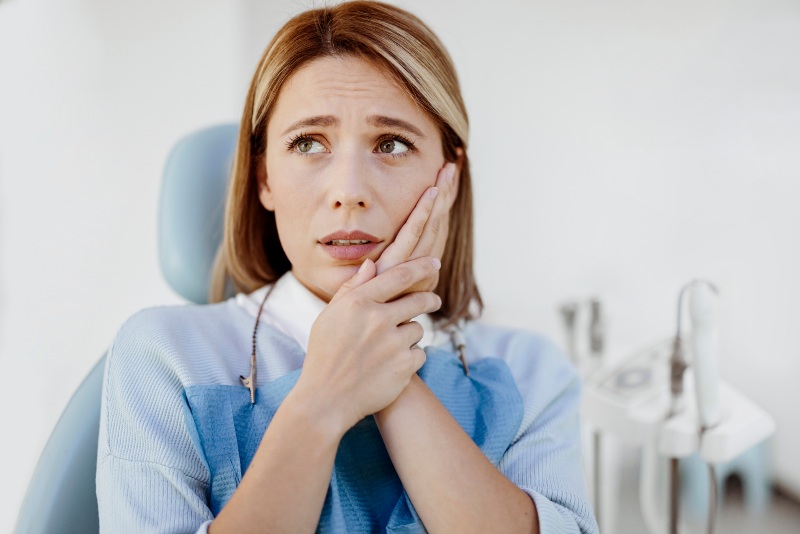 Woman complaining of toothache caused by tooth decay & in need of teeth extraction in Moberly, MO